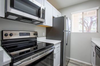 a kitchen with white cabinets and stainless steel appliances